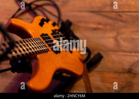 Eine E-Bass-Gitarre, die auf einem auf der Bühne platzierten Ständer basiert. Das Motiv wird von einem hellen Bühnenlicht beleuchtet. Geringe Schärfentiefe, Motiv inten Stockfoto