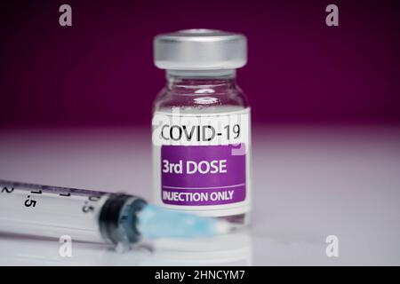 Medizinische Spritze und Glasfläschchen mit 3D Dosen Booster von Coronavirus-Impfstoff vor purpurem Hintergrund platziert Stockfoto