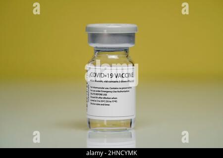 Medizinische Glasfläschchen mit Coronavirus-Impfstoff auf gelben Hintergrund gelegt Stockfoto