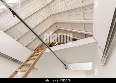 Von unten Leiter führt zu geräumigen Dachgeschoss Zimmer mit Holzdecke auf großes Haus Stockfoto