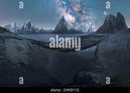 Malerische Landschaft mit klarem Fluss, der in der Dämmerung durch steinige Klippen auf der Lofoten-Insel unter Sternenhimmel fließt Stockfoto