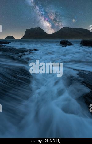 Malerische Landschaft mit klarem Fluss, der in der Dämmerung durch steinige Klippen auf der Lofoten-Insel unter Sternenhimmel fließt Stockfoto