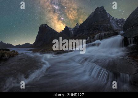 Malerische Landschaft mit klarem Fluss, der in der Dämmerung durch steinige Klippen auf der Lofoten-Insel unter Sternenhimmel fließt Stockfoto