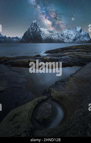 Malerische Landschaft mit klarem Fluss, der in der Dämmerung durch steinige Klippen auf der Lofoten-Insel unter Sternenhimmel fließt Stockfoto