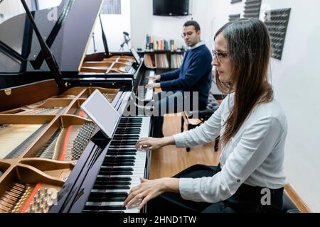 Seitenansicht fokussierter männlicher und weiblicher Schüler, die in der Musikschule Melodien am Klavier spielen Stockfoto
