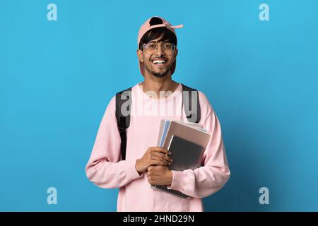Positive indische Kerl Student posiert auf blauem Hintergrund Stockfoto