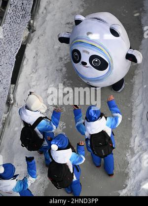 Peking, China. 16th. Februar 2022. Ein Bing Dwen Dwen, Maskottchen der Olympischen Winterspiele 2022 in Peking, interagiert mit Freiwilligen im Nationalen Alpinen Ski-Zentrum in Yanqing, Peking, der Hauptstadt Chinas, am 16. Februar 2022. Quelle: Lian Zhen/Xinhua/Alamy Live News Stockfoto