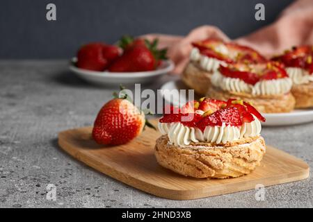 Choux Gebäck. Craquelin Choux Biscuits. Knusprige Cremepuffs mit Cremefüllung und Erdbeeren. Stockfoto