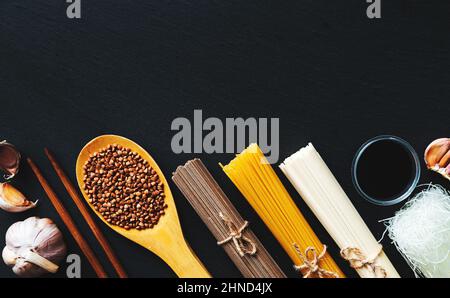 Nudeln aus verschiedenen Ländern. Soba, udon, Spaghetti, funchose. Schwarzer Hintergrund, flaches Lay, Kopierbereich. Hintergrund der Speisen. Stockfoto