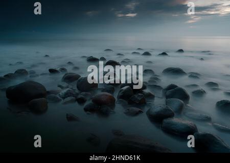 Schöne Scseascape Landschaft des Meeres nach Sonnenuntergang genommen , während der blauen Stunde , verschönert kaufen alle diese abgerundeten Felsen und den Lichtstrahl . Stockfoto
