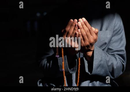 Nahaufnahme der Hände eines muslimischen Mannes, der betet und Gebetsperlen hält Stockfoto