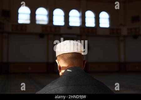 Rückansicht des Kopfes eines jungen muslimischen Mannes, während er in einer Moschee betet Stockfoto