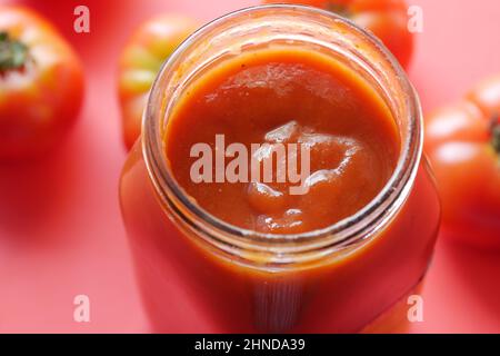 Tomatensauce in einem kleinen Glas mit frischer Tomate auf Tabelle Stockfoto