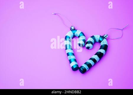 Weihnachtsbaumschmuck in Form eines Karamells in Form eines Rohres auf einem violetten Hintergrund, Weihnachtsmann's Weihnachten gestreiften Zuckerrohr in den sh gelegt Stockfoto