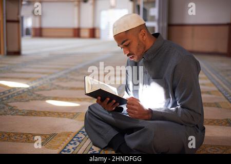 Porträt eines jungen muslimischen Mannes, der den Koran in einer Moschee liest Stockfoto