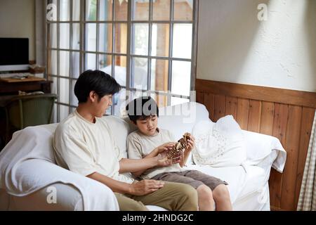 Japanische Eltern Und Kind Sitzen Auf Dem Sofa Stockfoto