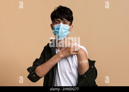 Junger inder mit Gesichtsmaske, der zeigt, dass er geimpft wurde Stockfoto