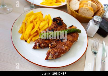 Gebackene würzige Schweinetrottern mit Kartoffeln auf dem Teller serviert Stockfoto