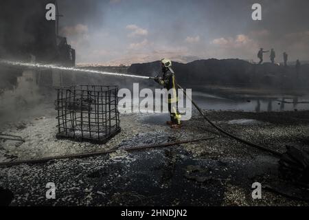 Dana, Syrien. 16th. Februar 2022. Mitglieder der syrischen Zivilverteidigung, bekannt als Weißhelme, arbeiten daran, ein Feuer zu löschen, das in einem Treibstofflager ausbrach, als Folge eines Raketenangriffs des syrischen Regimes und russischer Streitkräfte auf das Dorf Tarminin in der Nähe der Stadt Dana. Nach Angaben der Weißhelme wurden bei einem Artilleriebeschuss auf einem Brennstoffmarkt, der angeblich einer dschihadistischen Gruppe angehört, vier Zivilisten getötet und zwei weitere verletzt. Quelle: Anas Alkharboutli/dpa/Alamy Live News Stockfoto