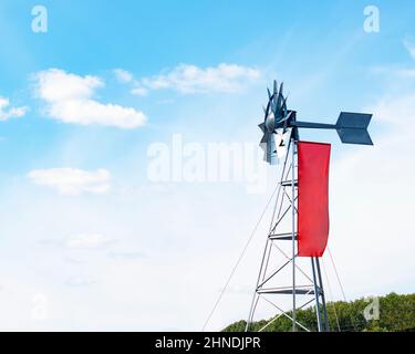 Windmühle Wetterfahne mit roter Flagge auf blauem Himmel Hintergrund Stockfoto