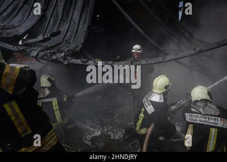 Dana, Syrien. 16th. Februar 2022. Mitglieder der syrischen Zivilverteidigung, bekannt als Weißhelme, arbeiten daran, ein Feuer zu löschen, das in einem Treibstofflager ausbrach, als Folge eines Raketenangriffs des syrischen Regimes und russischer Streitkräfte auf das Dorf Tarminin in der Nähe der Stadt Dana. Nach Angaben der Weißhelme wurden bei einem Artilleriebeschuss auf einem Brennstoffmarkt, der angeblich einer dschihadistischen Gruppe angehört, vier Zivilisten getötet und zwei weitere verletzt. Quelle: Anas Alkharboutli/dpa/Alamy Live News Stockfoto