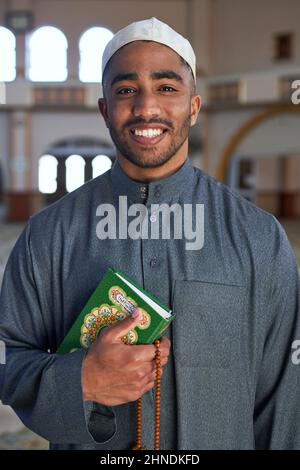 Porträt eines muslimischen Mannes, der lächelt und den Koran und die Gebetsperlen hält Stockfoto