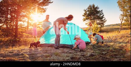 Gruppe der Menschen, die das Zelt auf der Natur in der Nähe des Meeres aufschlagen. Stockfoto