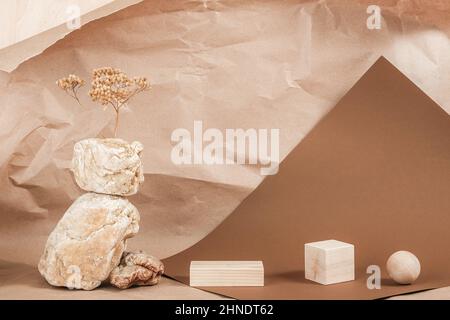 Kreative Podium für Kosmetik oder Sie Merchandise, Produkte. Grundriss aus geometrischen Holzformen, Steinen und getrockneten Blumen auf braunem beigefarbenem Papier Stockfoto