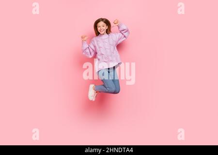 Foto von charmanten hübschen Mädchen gestrickt Pullover zeigt sich springen hoch isoliert rosa Farbe Hintergrund gekleidet Stockfoto