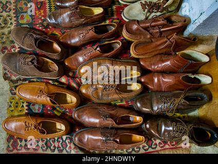 Alte gebrauchte Herrenschuhe und -Stiefel, die auf einem alten Teppich auf dem Brooklyn Flea Market ausgelegt wurden Stockfoto