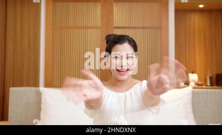Die Frau begrüßt die Kamera in ihrem Schlafzimmer glücklich Stockfoto