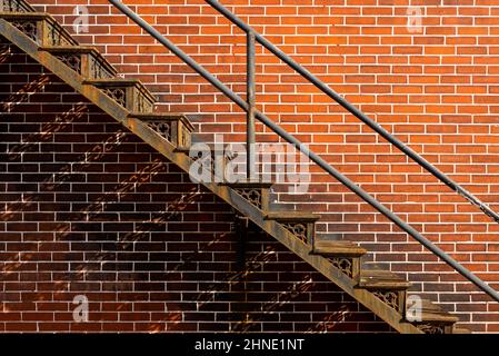 Alte verrostete Metalltreppe mit Backsteinmauer im Hintergrund. Stockfoto