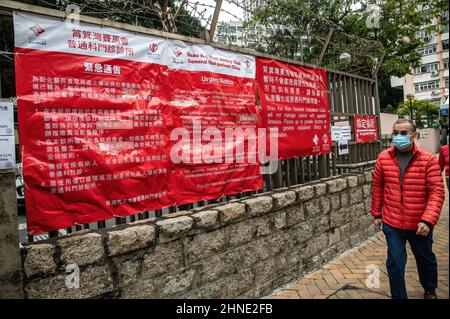 Ein Mann kommt an einem großen Informationsbanner vor der Shau Kei Wan Jockey Club Clinic vorbei und informiert die Besucher, dass es keine Patienten mit COVID-19-Patienten mehr versorgt. Als Reaktion auf den exponentiellen Anstieg der COVID-19-Fälle, die die Krankenhäuser Hongkongs überlasten, hat die Regierung in der ganzen Stadt spezielle Kliniken eingerichtet, um diejenigen zu behandeln, die positive Tests durchführen. Die Kliniken sollen Menschen mit leichten Symptomen behandeln, mit Tagesquoten und einem bald startenden Taxi-Transportprogramm. Hongkong befindet sich derzeit in der fünften Phase der Pandemie und registriert Tausende von neuen Fällen pro Tag. Stockfoto