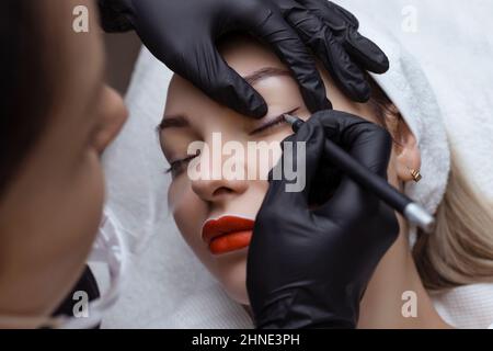 Dauerhaftes Make-up. Kosmetologe Tattoo Künstler wendet eine Kontur auf das Augenlid des Kunden für die anschließende Anwendung der Augen Tätowierung Stockfoto