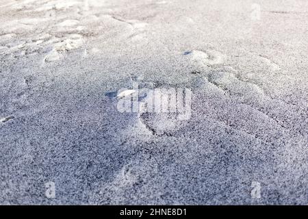 Schwarzer Ruß aus dem Kesselraum auf weißem Schnee. Natürlicher Hintergrund. Schnee gemischt mit Kohleroß, schlechte Ökologie. Umweltverschmutzung Stockfoto