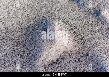 Schwarzer Ruß aus dem Kesselraum auf weißem Schnee. Natürlicher Hintergrund. Schnee gemischt mit Kohleroß, schlechte Ökologie. Umweltverschmutzung Stockfoto