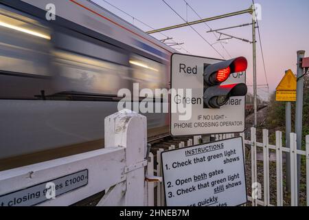 Zug, der Bahnübergang auf der Hauptlinie nach Norfolk bei Margaretting Essex passiert Stockfoto
