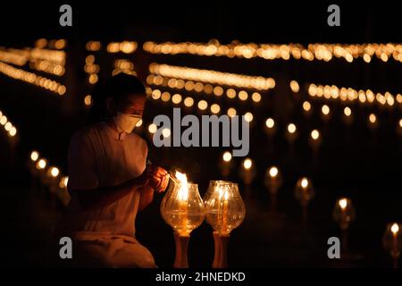 Pathum Thani, Thailand. 16th. Februar 2022. Gläubige sahen während der Zeremonie im Dhammakaya Tempel Kerzen anzünden.Makha Bucha Day, Dhammakaya Tempel veranstaltete eine virtuelle internationale Makha Bhucha Zeremonie, indem er eine Million Laternen anzündete. Die Mönche auf der ganzen Welt singen und meditieren gemeinsam, während einige Gläubige per Zoom an der Zeremonie teilnehmen. Kredit: SOPA Images Limited/Alamy Live Nachrichten Stockfoto