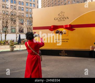 Vor dem ValentineÕs Day am Dienstag, dem 8. Februar 2022, auf dem Herald Square in New York erhalten die Menschen Proben und fotografieren eine riesige Süßigkeitenkiste bei der Aktivierung einer Schokoladenmarke von Godiva. (© Richard B. Levine) Stockfoto