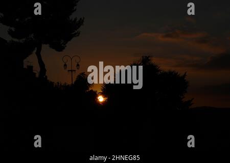 Winter Sonnenuntergang in Haut de Cages, Cagnes sur Mer, Frankreich. Mediterraner Sonnenuntergang zwischen Vegetation und dunklem Himmel. Stockfoto