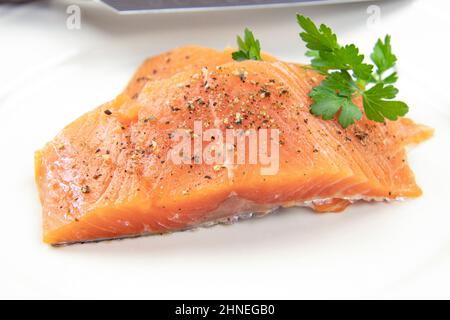 Rohes Lachssteak auf weißem Hintergrund mit Petersilie Stockfoto