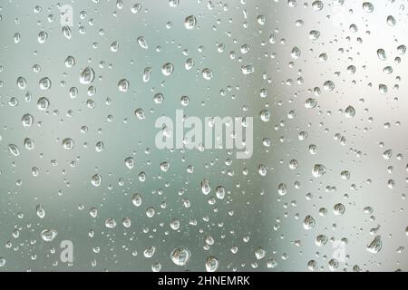 Regentropfen auf einer Fensterscheibe bei regnerischem Wetter Stockfoto
