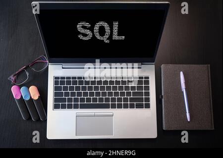 Draufsicht auf Laptop mit Text-SQL. SQL-Beschriftung auf Laptop-Bildschirm und Tastatur. Lernen Sie SQL-Sprache, Computerkurse, Schulungen. Stockfoto