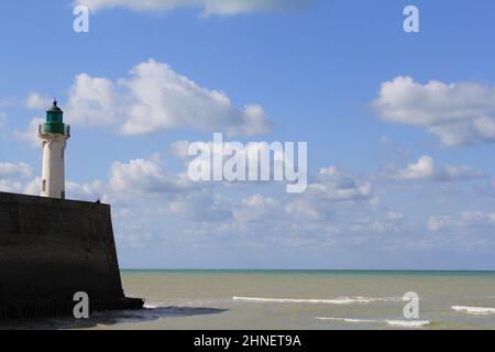 Wunderschöne Seeseite an der französischen Küste in der normandie in Saint-Valery-en-Caux mit einem blauen Himmel voller Wolken und einem Pier mit einem weißen Leuchtturm davor Stockfoto