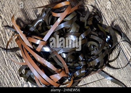 Audiofilm auf dem Tisch. Ein Magnetfilm, der aus einer defekten Kassette gezogen wurde. Audiokassette. Retro-Musikmedium, kompakte Kassette für Tonbandgerät. Stockfoto