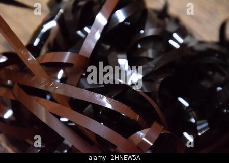 Audiofilm auf dem Tisch. Ein Magnetfilm, der aus einer defekten Kassette gezogen wurde. Audiokassette. Retro-Musikmedium, kompakte Kassette für Tonbandgerät. Stockfoto