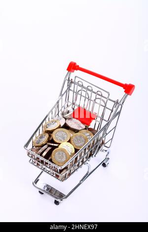 Mini-Einkaufswagen mit Draht-Einkaufswagen, gefüllt mit britischen Pfund-Münzen und fünfzig Pence-Münzen, Stockfoto