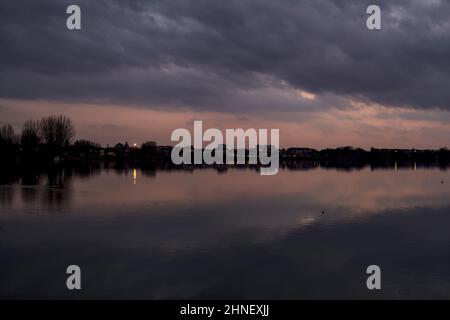 See mit Boys und der Himmel in der Dämmerung auf dem Wasser gegossen Stockfoto