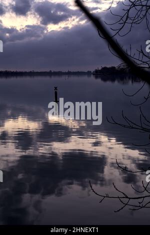 See mit Boys und der Himmel in der Dämmerung auf dem Wasser gegossen Stockfoto