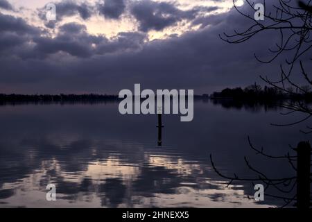 See mit Boys und der Himmel in der Dämmerung auf dem Wasser gegossen Stockfoto